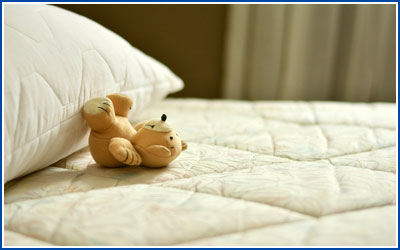 Mattress, pillow, and upside down teddy bear